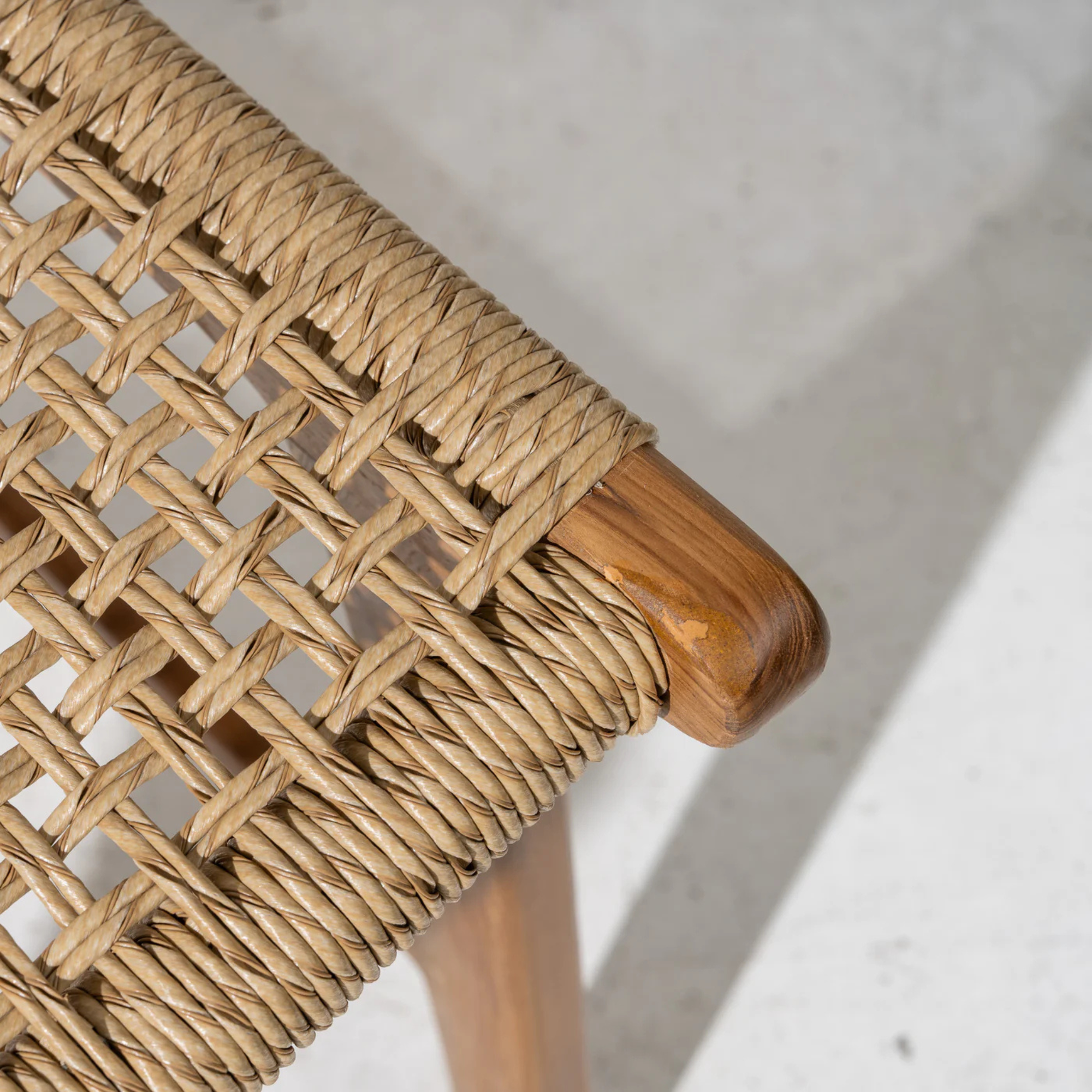 Close-up of a woven dining chair with teak frame